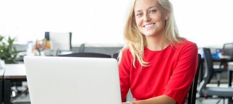 Happy attractive businesswoman typing on laptop